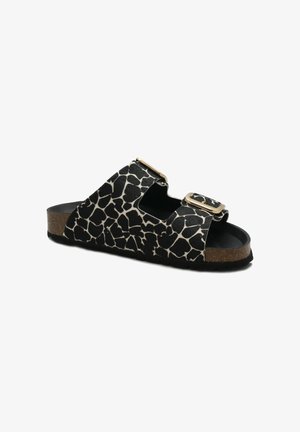 Sandalo in stampa giraffa bianco e nero con due fibbie dorate regolabili e suola in sughero, mostrato su sfondo bianco.