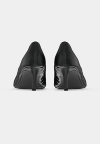 Mustad kõrge kontsaga kingad, millel on siledast nahast pealiskate, terav nina ja tekstureeritud tagumine detail. Stiletto konts rõhutab disaini.