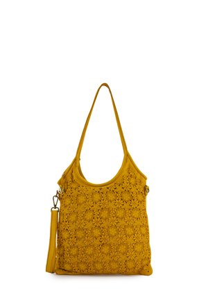 Musztardowożółta torebka na ramię z kwiatowym wzorem wyciętym laserowo oraz odpinanym paskiem na białym tle.