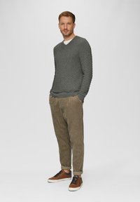 Grau strukturierter Strickpullover mit V-Ausschnitt, kombiniert mit hellbraunen Cordhosen und braunen Sneakers mit schwarzen Akzenten.