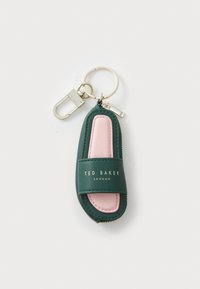 Green and pink leather keychain in a sandal shape, featuring gold logo text and a gold hardware clasp. Smooth texture with contrasting colors.