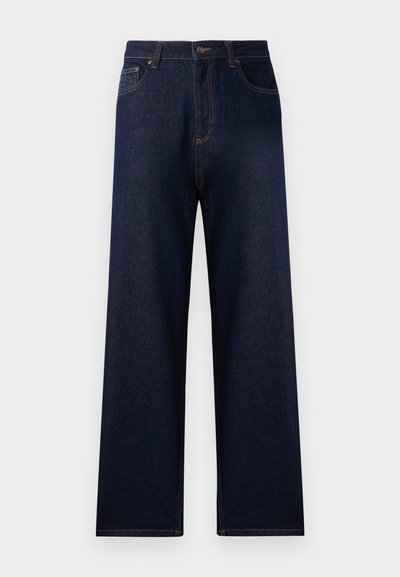 Tamno plave traperice s visokim strukom, širokim nogavicama i kontrastnim šavovima. Karakteristike uključuju prednje džepove i jedan stražnji džep.