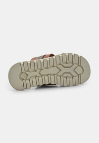 Sandal in marrone con design della cinghia a fantasia. Suola in gomma spessa e testurizzata con scanalature profonde per una buona aderenza. Suola flessibile di colore chiaro.