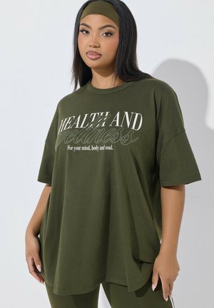 Młoda kobieta z długimi ciemnymi włosami nosi oliwkowo-zieloną opaskę na głowę i oversize'owy t-shirt z napisem „Zdrowie i dobre samopoczucie dla twojego umysłu, ciała i duszy.”