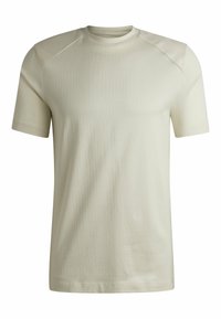 T-shirt a maniche corte di un beige chiaro con un tessuto a coste testurizzato. Presenta dettagli lisci sulle spalle e un classico scollo rotondo.