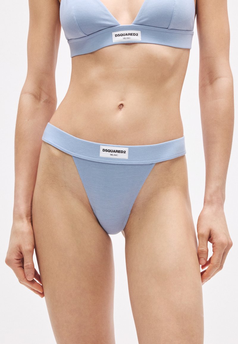 Világoskék tanga puha anyagból, széles derékszalaggal. Elöl márkázott címkével, minimalistán tervezve, sima textúrával.