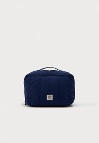 Ναυτικό μπλε ορθογώνια καπιτονέ τσάντα καλλυντικών με χερούλι στην κορυφή, κλείσιμο με φερμουάρ και μικρή ετικέτα λογότυπου στο κεντρικό μπροστινό μέρος.