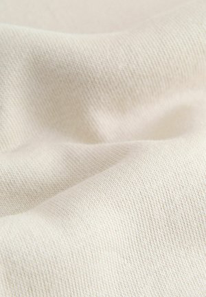 Helles beige Baumwollgewebe mit glatter Textur und subtilen Rippmustern, die sanfte Falten und Knicke zeigen.