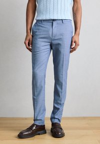 Ανοιχτό μπλε παντελόνι με κοψίματα σε υφασμάτινη υφή, διαθέτει επίπεδη μπροστινή όψη, πλαϊνές τσέπες και κομψή ίσια γραμμή. Συνδυασμένο με σκούρα καφέ παπούτσια.