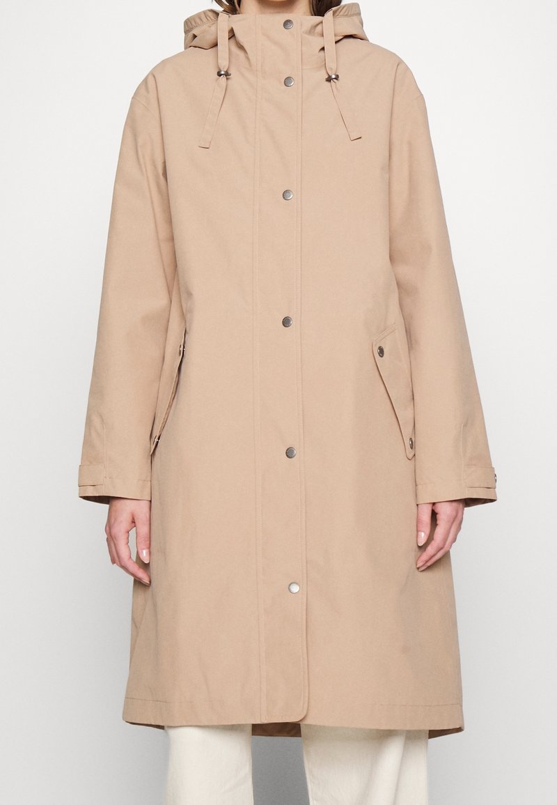 Beiger Parka mit Kapuze, vorderer Druckknopfleiste, Seitentaschen und verstellbaren Kordeln. Aus glattem Stoff gefertigt mit lockerem Schnitt.