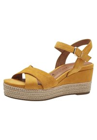 Sandalias de cuña de ante amarillo con un tacón de yute trenzado y un diseño de tiras cruzadas. Presentan una correa en el tobillo trasero con una hebilla de metal.