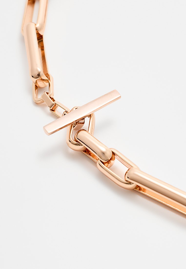 Collana a catena in oro rosa con anelli allungati e cilindrici e chiusura a barra piatta. Texture liscia e finitura lucida.