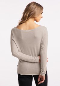 Lichtbeige lange mouwtop met een brede halslijn en ribbeltextuur, voorzien van een licht gebogen onderrand en zichtbare stikseldetails.