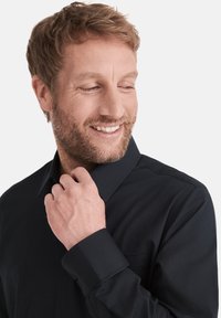 Dunkelblaues Button-Down-Hemd mit klassischem Kragen und langen Ärmeln, ausgestattet mit einer Brusttasche und glatter Textur. Modell passt den Kragen an.