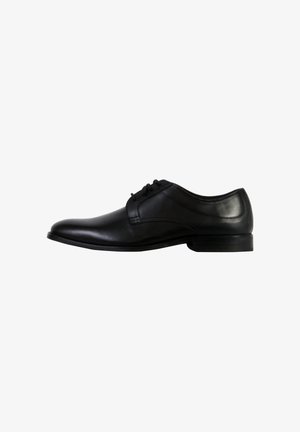 Chaussure Oxford en cuir noir à finition lisse, design à lacets, bout arrondi, et petit talon empilé. Vue de côté, style minimaliste.