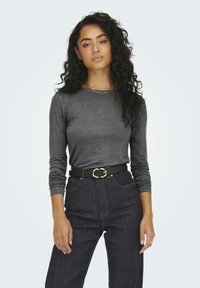 Gray long-sleeve top made of soft fabric, paired with high-waisted dark denim jeans and a black belt featuring a gold buckle detail.
