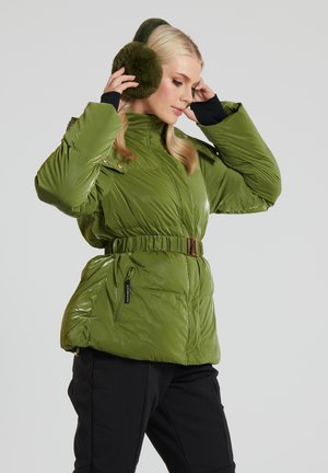 Green puffer jacket with a shiny finish, belted waist, zippered pockets, and a high collar. Model wears dark pants and fur ear muffs.