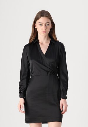 Abito avvolgente in seta nera con maniche lunghe, scollatura a V e silhouette aderente. Tessuto morbido con design minimalista.