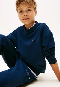 Navy blauwe sweatshirt en sweatpants set, gemaakt van zacht materiaal. Opmerkelijke details zijn onder andere geborduurd logo en geribde manchetten.