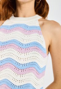 Adīta halter top ar viļņu rakstu pasteļa zilos, rozā un baltos toņos. Ievērojama teksta apdare un pieguļoša dizaina.