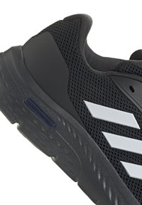 Chaussure de sport noire avec tige en mesh, trois rayures blanches, semelle texturée et marquage "CLOUD FOAM WALK". Accents lisses au niveau du talon.