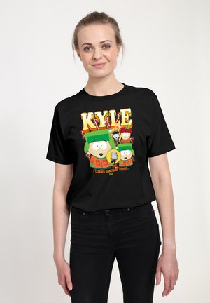 Junge Frau trägt ein schwarzes T-Shirt mit der animierten Figur Kyle aus South Park mit dem Text „Ich habe heute etwas gelernt.“
