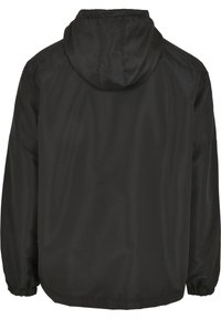 Svart jacka med huva, tillverkad av ett slätt, lätt material. Har elastiska mudd och en avslappnad passform. Minimalistisk design.