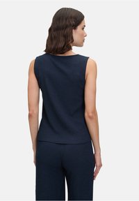 Navy mouwloos topje met een ronde hals en ribbeltextuur, gecombineerd met bijpassende ribbelbroek, gezien van achteren.