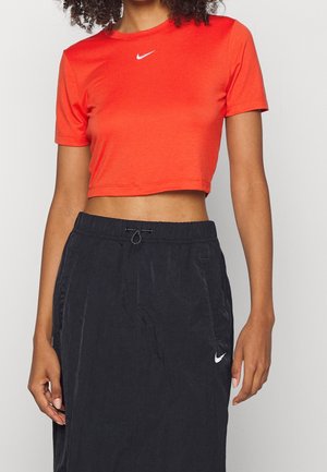 T-shirt rouge raccourci avec un logo Nike blanc, associé à une jupe élastique navy foncé avec des poches latérales et un cordon de serrage.