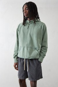 Lys grøn bomulds hoodie med en kengurulomme og hætte med snoretræk, parret med mørkegrå fløjlshorts med elastisk talje.