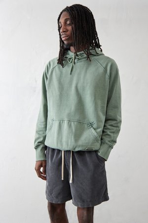 Haut en coton vert clair avec une poche kangourou et une capuche à cordon, associé à un short en velours côtelé gris foncé avec une taille élastique.