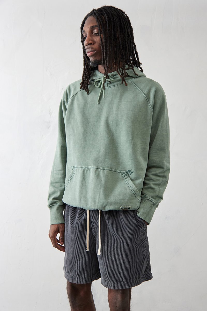 Lys grøn bomulds hoodie med en kengurulomme og hætte med snoretræk, parret med mørkegrå fløjlshorts med elastisk talje.