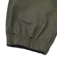 Olivgrüner elastischer Saum mit Manschette aus glattem Stoff; verfügt über eine geraffte Textur und verstärkte Nähte für Langlebigkeit.