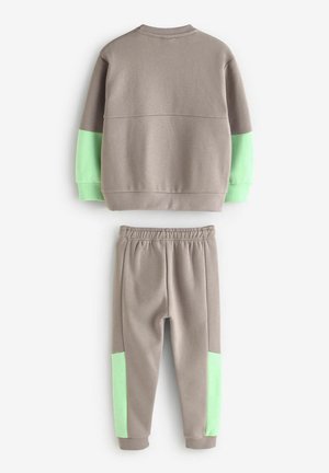 Sweatshirt gris avec des manches à accent vert et un pantalon assorti avec des panneaux latéraux verts. Fabriqué en tissu doux et texturé.