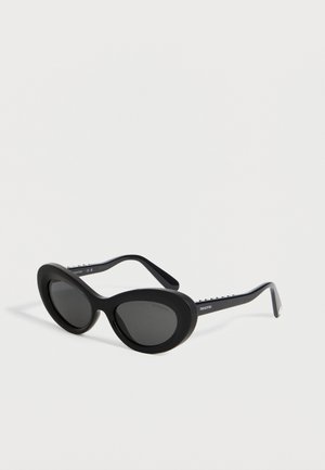 Black oval-shaped sunglasses with thick frames and dark lenses, featuring small decorative elements on the temples and a brand logo.