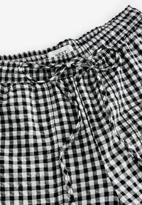 Short à taille élastique à carreaux noir et blanc avec un cordon en tissu noué et une étiquette de marque visible indiquant NEXT.