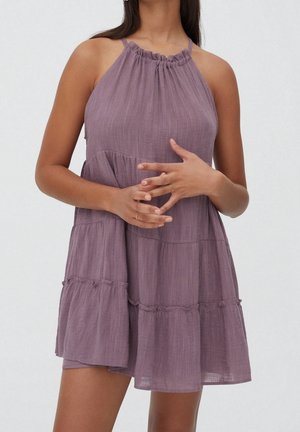 Robe halter violette en tissu texturé, avec un décolleté froncé, une jupe à volants et une coupe ample. Accentuée par des bords enroulés.