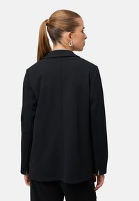 Czarna, dopasowana marynarka z pojedynczym rozcięciem z tyłu, usztywnionymi ramionami i długimi rękawami. Gładki materiał o schludnym, minimalistycznym designie.