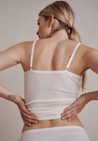 Hvid camisole med justerbare spaghetti-stropper og et blødt, letvægtsstof. Glat tekstur, tætsiddende design og enkelt snit.
