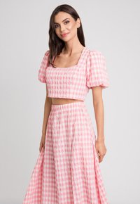Różowa sukienka w kratkę składająca się z dwóch części, z krótkim topem z bufkami i zwiewną maxi spódnicą, obie części wykonane z teksturowanej tkaniny.