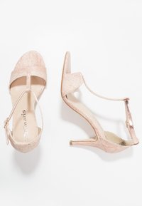 Růžové sandály na vysokém podpatku s strukturovaným svrškem, designem T-popruhu, nastavitelným řemínkem kolem kotníku a tenkým stiletto podpatkem.