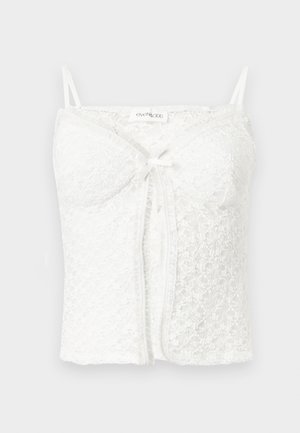 Camisole courte en dentelle blanche avec fines bretelles, bonnets rembourrés, nœud à l'avant et motif floral texturé.