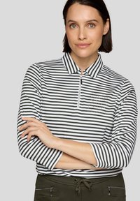 Gestreiftes Hemd in Grün- und Weißtönen, mit halbem Reißverschlusskragen, dreiviertel Ärmeln, kleinem Taschen mit Nieten-Detail. Glatte Stofftextur.