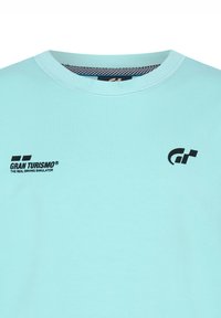 Camiseta de algodón azul claro con el logo "GRAN TURISMO" y el texto "THE REAL DRIVING SIMULATOR" en negro, diseño de cuello redondo con collar texturizado.