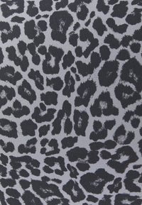 Tkanina w panterkę z nieregularnymi czarnymi plamami o różnych rozmiarach na jasnoszarym tle. Miękka struktura, idealna do odzieży lub akcesoriów.