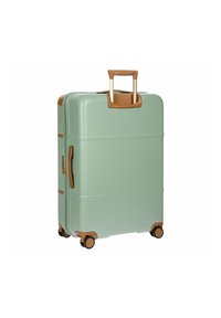 Valigia rigida di colore verde menta, con manico e dettagli marroni, quattro ruote e forma rettangolare con scanalature per una migliore presa.