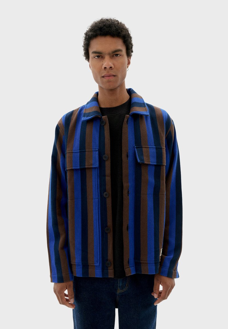 Gestreepte jas in blauw en bruin, gemaakt van dikke stof, met een knoopsluiting aan de voorkant, twee borstzakken en een kraag.