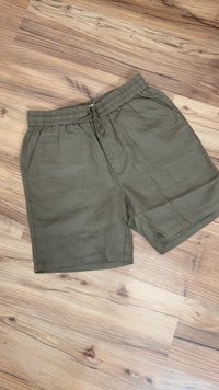 Olivgrüne Leinen-Shorts mit einem elastischen Bund, Kordelzugverschluss und Seitentaschen. Glatte Textur und lockerer Schnitt.