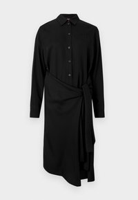 Crna haljina s dugim rukavima, ovratnikom, kopčanjem na gumbe sprijeda i remenom oko struka. Ima asimetrični rub i glatku tkaninu.