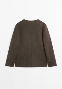 Brun uldjakke med et enkelt design, rund halsudskæring, lange ærmer og tre knapper på manchetterne. Bagfra vist.